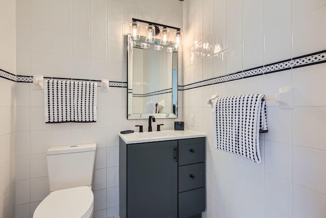 bathroom featuring vanity, toilet, and tile walls