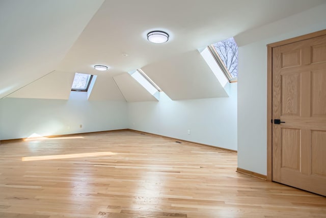 bonus room featuring light hardwood / wood-style floors and vaulted ceiling with skylight