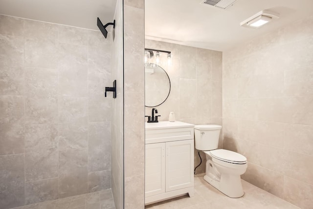 bathroom featuring vanity, tiled shower, tile walls, and toilet