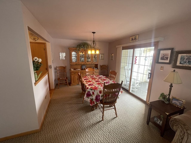 dining space with carpet floors and a chandelier