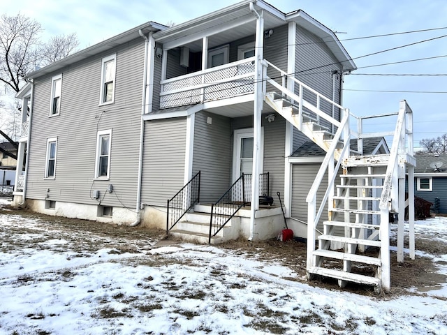 snow covered back of property with a balcony