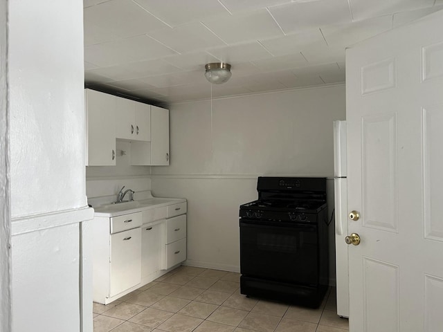 kitchen featuring white cabinets, light tile patterned flooring, sink, and black range with gas stovetop