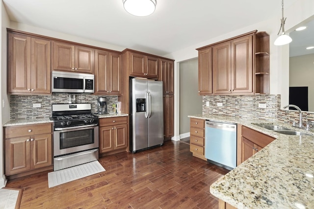 kitchen featuring pendant lighting, sink, appliances with stainless steel finishes, backsplash, and light stone countertops