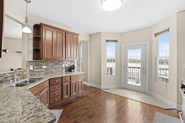 kitchen featuring pendant lighting, sink, light stone countertops, dark hardwood / wood-style flooring, and decorative backsplash