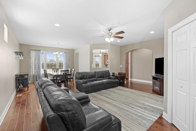 living room with dark hardwood / wood-style flooring and ceiling fan with notable chandelier