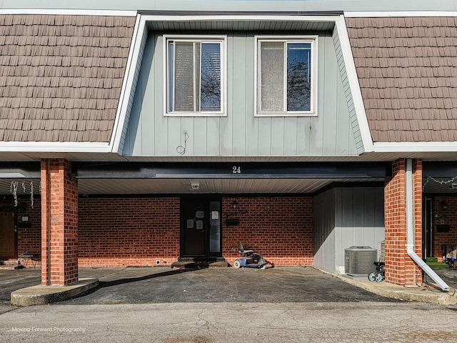 view of front of property featuring brick siding, central AC unit, and aphalt driveway