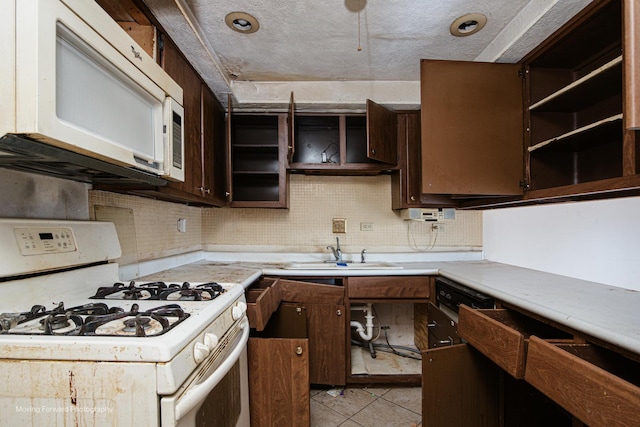 kitchen featuring dark brown cabinets, sink, light tile patterned floors, and white appliances