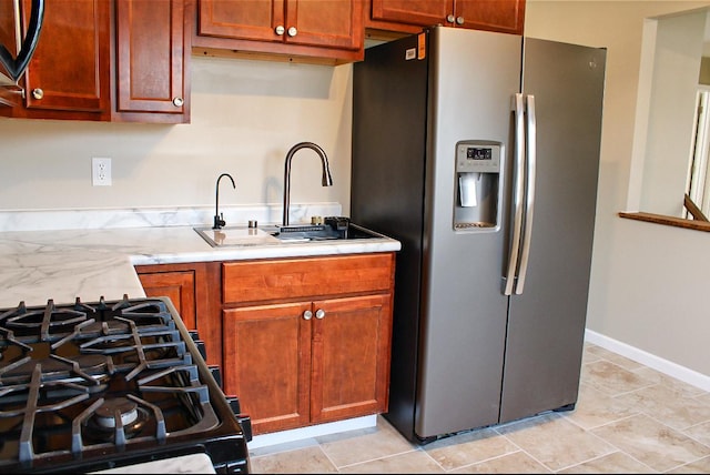 kitchen featuring sink, light tile patterned floors, range with gas cooktop, and stainless steel fridge with ice dispenser