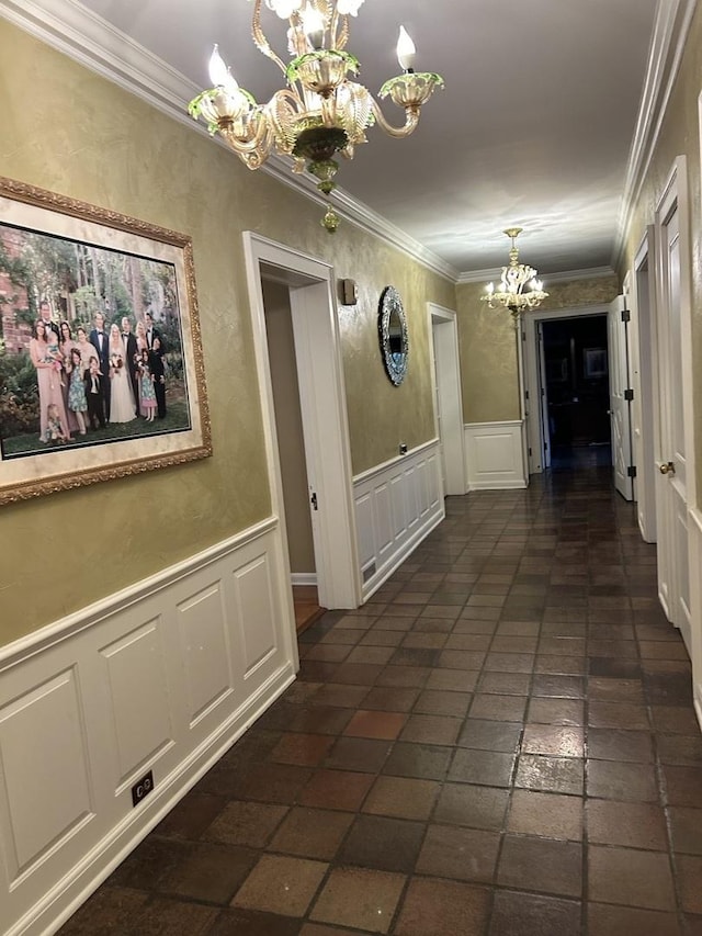hallway featuring an inviting chandelier, ornamental molding, a wainscoted wall, and a decorative wall