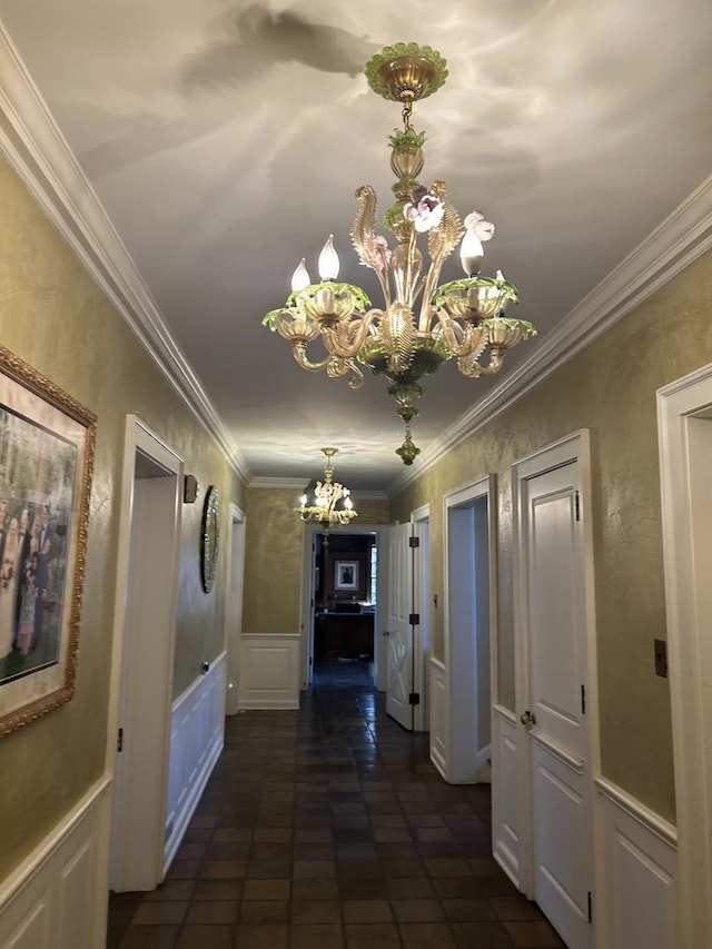 hall with an inviting chandelier, ornamental molding, and a decorative wall