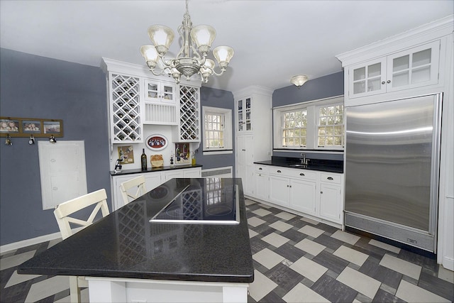 kitchen featuring glass insert cabinets, dark countertops, white cabinets, and a chandelier