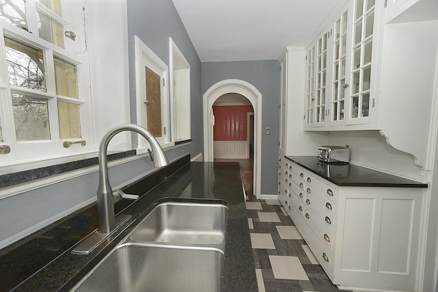 2221 Twin Oak Rd, Peru, IL 61354 - kitchen featuring a sink, arched walkways, white cabinets, dark countertops, and glass insert cabinets