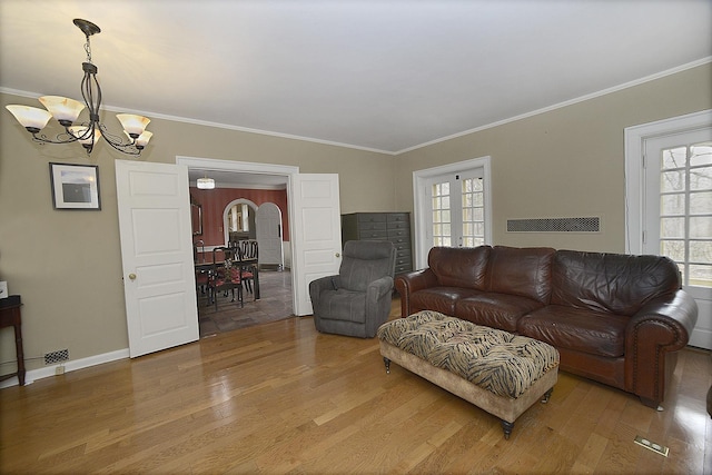 living room featuring arched walkways, an inviting chandelier, a healthy amount of sunlight, and wood finished floors