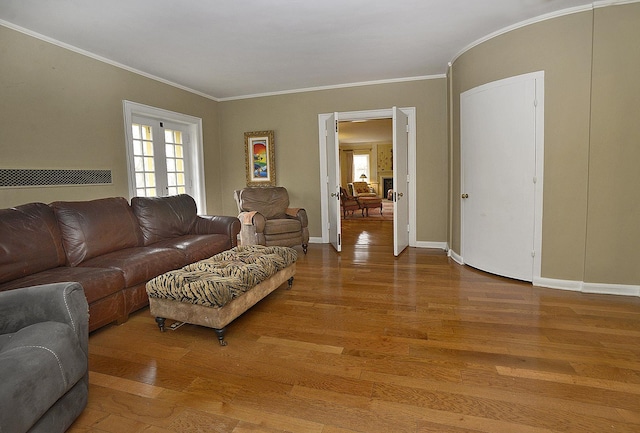 living area featuring baseboards, ornamental molding, wood finished floors, and a healthy amount of sunlight