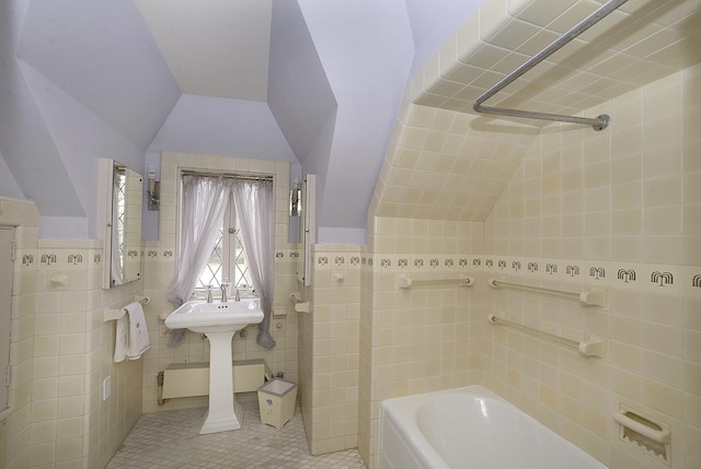full bath featuring tile patterned floors, lofted ceiling, a washtub, and tile walls