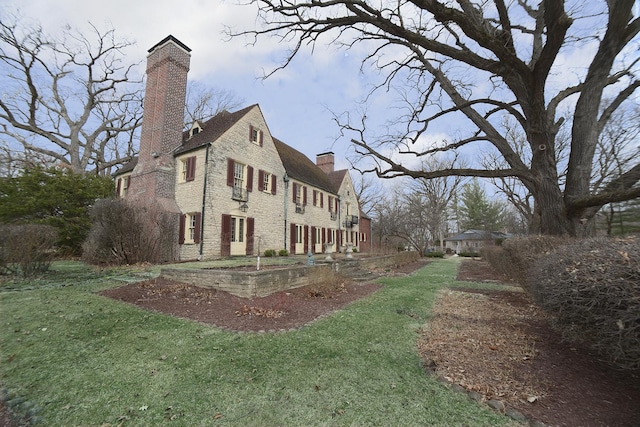 view of property exterior with a lawn, a chimney, and stone siding