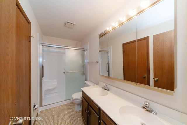 bathroom featuring tile patterned flooring, vanity, a shower with shower door, and toilet