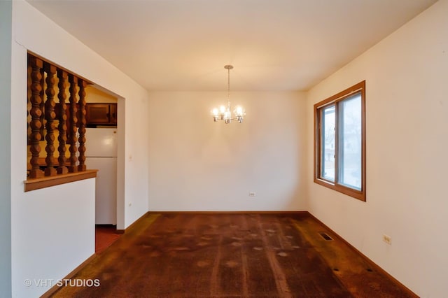 unfurnished dining area with dark colored carpet and an inviting chandelier