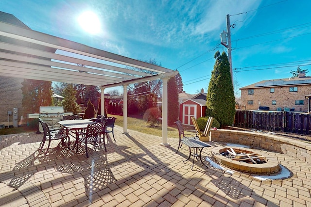 view of patio featuring an outdoor fire pit, a pergola, and a storage unit