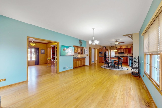 interior space featuring ceiling fan with notable chandelier and light hardwood / wood-style flooring