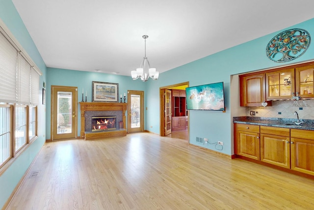 kitchen featuring sink, a chandelier, hanging light fixtures, light hardwood / wood-style flooring, and backsplash