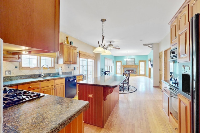 kitchen featuring sink, gas cooktop, black dishwasher, a kitchen island, and stainless steel oven