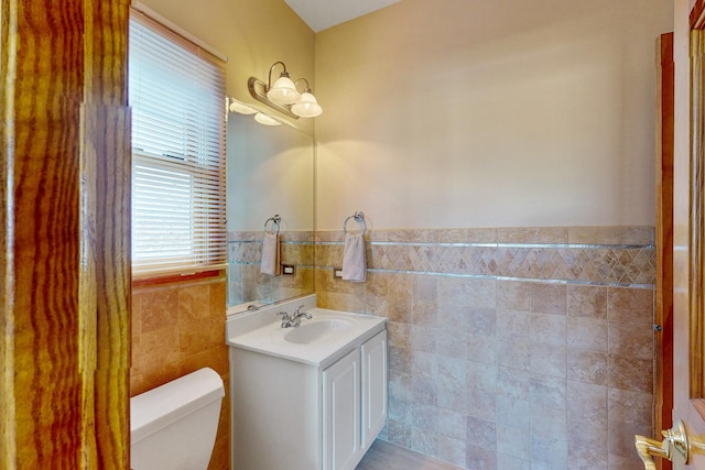 bathroom with vanity, tile walls, and toilet