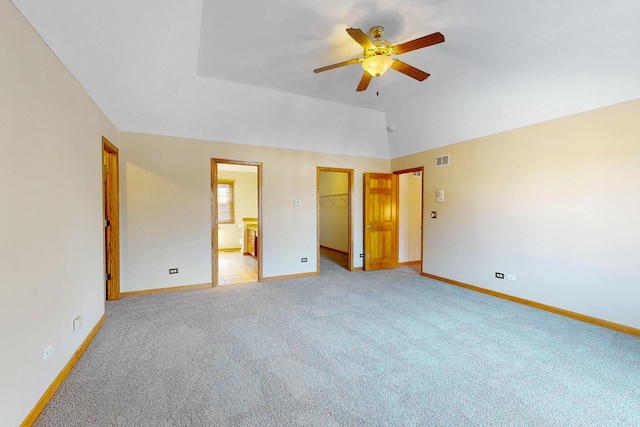 unfurnished bedroom with lofted ceiling, a walk in closet, ceiling fan, light carpet, and a closet