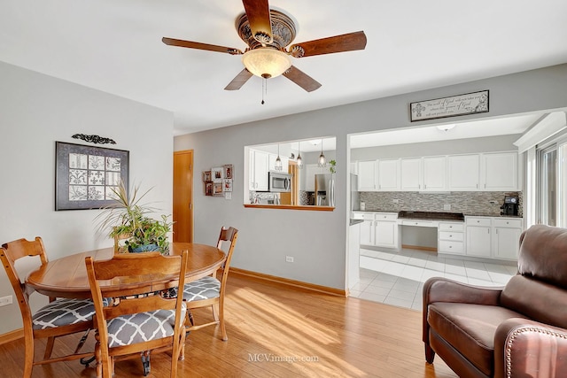 dining area with ceiling fan, built in desk, and light wood-type flooring