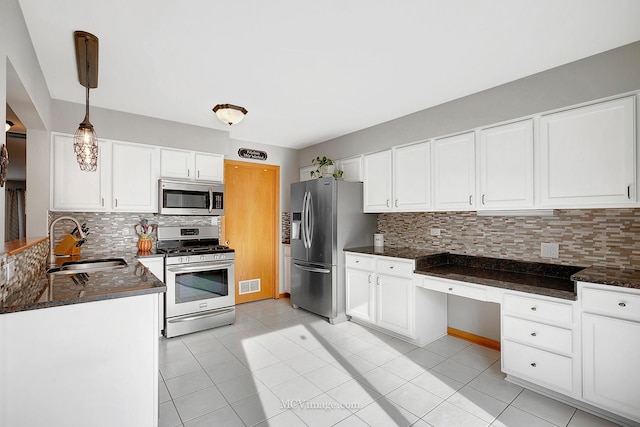 kitchen featuring sink, backsplash, appliances with stainless steel finishes, pendant lighting, and white cabinets