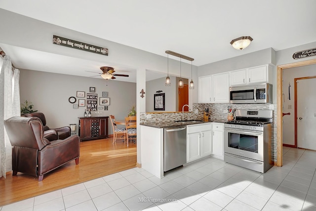 kitchen with white cabinetry, sink, hanging light fixtures, light tile patterned floors, and stainless steel appliances