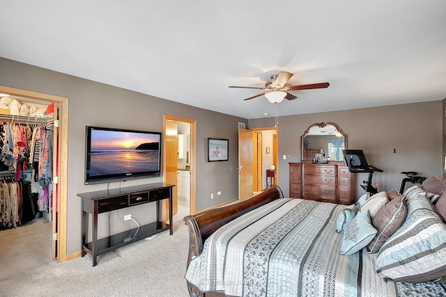 bedroom featuring ensuite bathroom, a walk in closet, light carpet, a closet, and ceiling fan