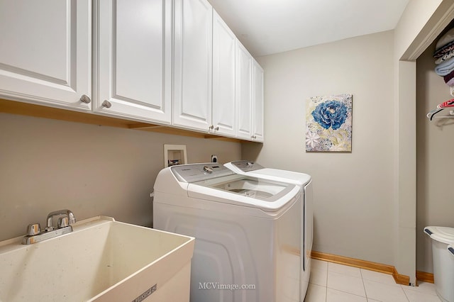 laundry area featuring sink, light tile patterned floors, cabinets, and washing machine and clothes dryer