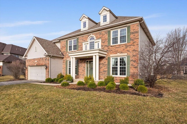 colonial inspired home featuring brick siding, a garage, driveway, and a front yard