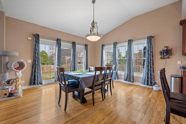 dining room featuring baseboards, vaulted ceiling, and light wood-style flooring