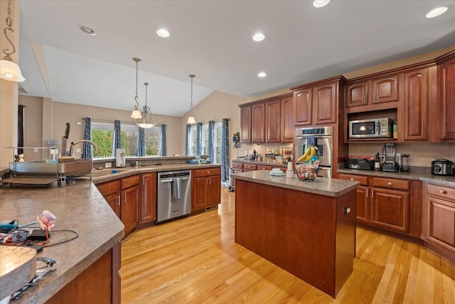 kitchen featuring lofted ceiling, a kitchen island, light wood-style floors, a sink, and stainless steel appliances