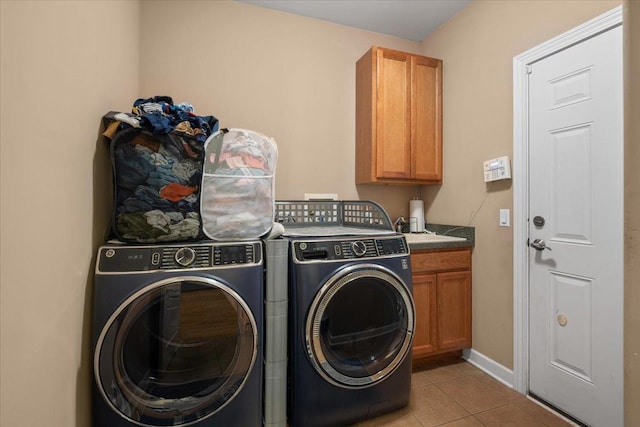 washroom featuring light tile patterned floors, baseboards, washing machine and dryer, and cabinet space