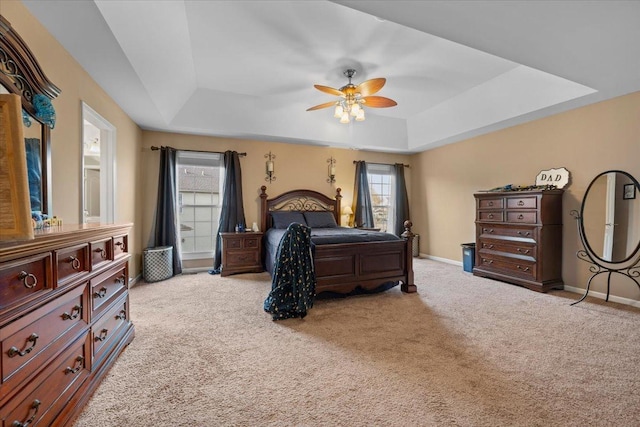 bedroom featuring carpet floors, a ceiling fan, baseboards, and a tray ceiling