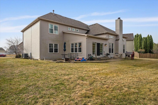 back of house featuring a yard, cooling unit, a chimney, and a patio area