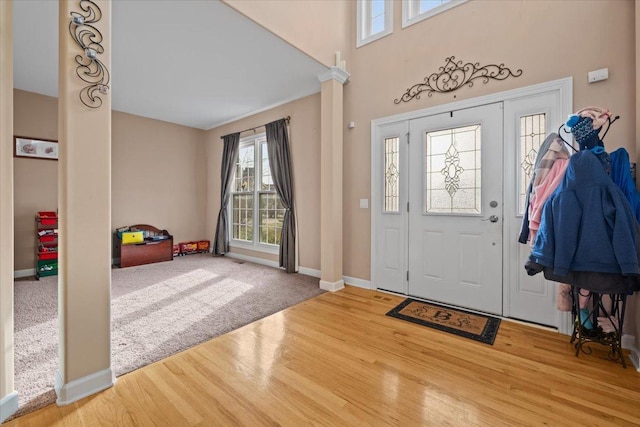 entrance foyer featuring baseboards, ornate columns, and wood finished floors