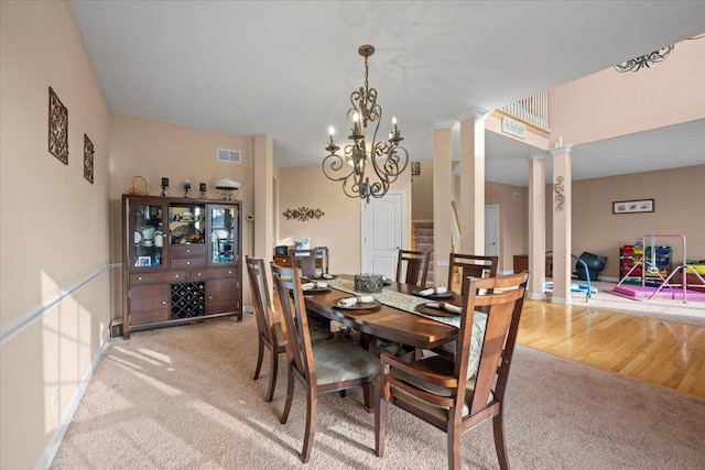 dining area with visible vents, decorative columns, a chandelier, and light colored carpet