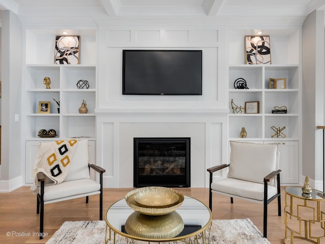 living room with built in shelves, a premium fireplace, beam ceiling, and light hardwood / wood-style flooring