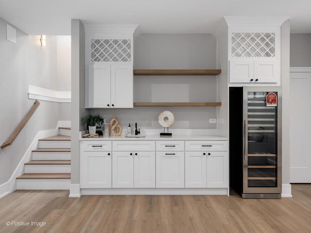 kitchen with light wood-type flooring, wine cooler, sink, and white cabinets