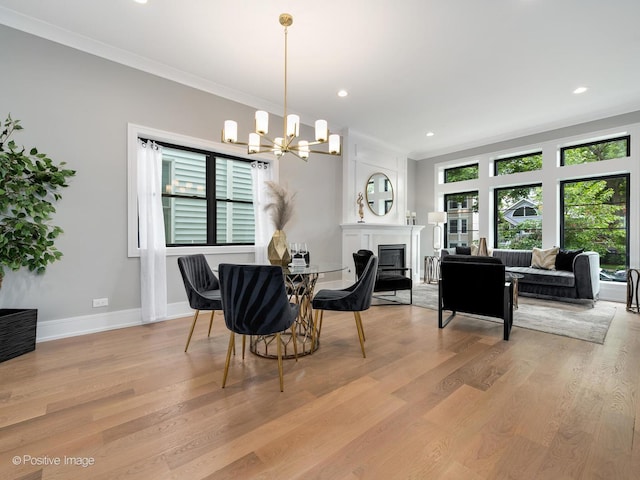 dining area with crown molding, a chandelier, and light hardwood / wood-style flooring