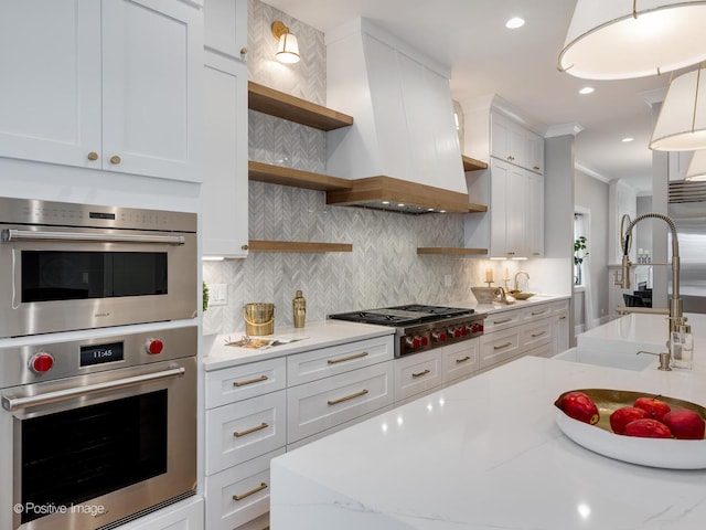 kitchen featuring stainless steel appliances, white cabinets, and premium range hood