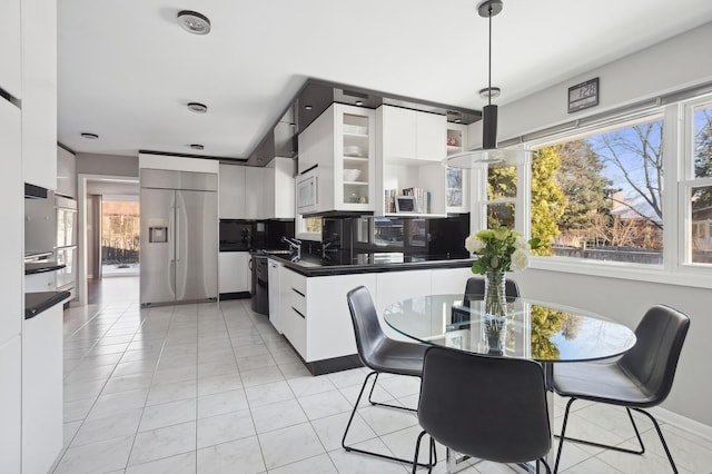 kitchen with decorative light fixtures, tasteful backsplash, white cabinetry, built in appliances, and light tile patterned floors