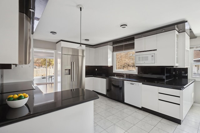 kitchen with decorative backsplash, built in appliances, white cabinets, and decorative light fixtures