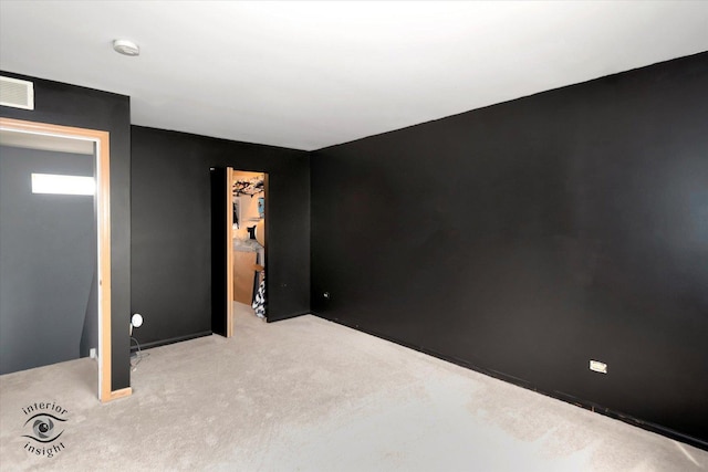 spare room featuring light carpet and visible vents