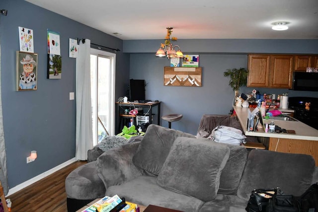 living room with sink, a notable chandelier, and dark hardwood / wood-style flooring