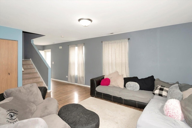living room featuring stairway, baseboards, wood finished floors, and visible vents